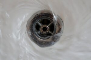 Water Swirling Down A Metal Drain In A Sink.